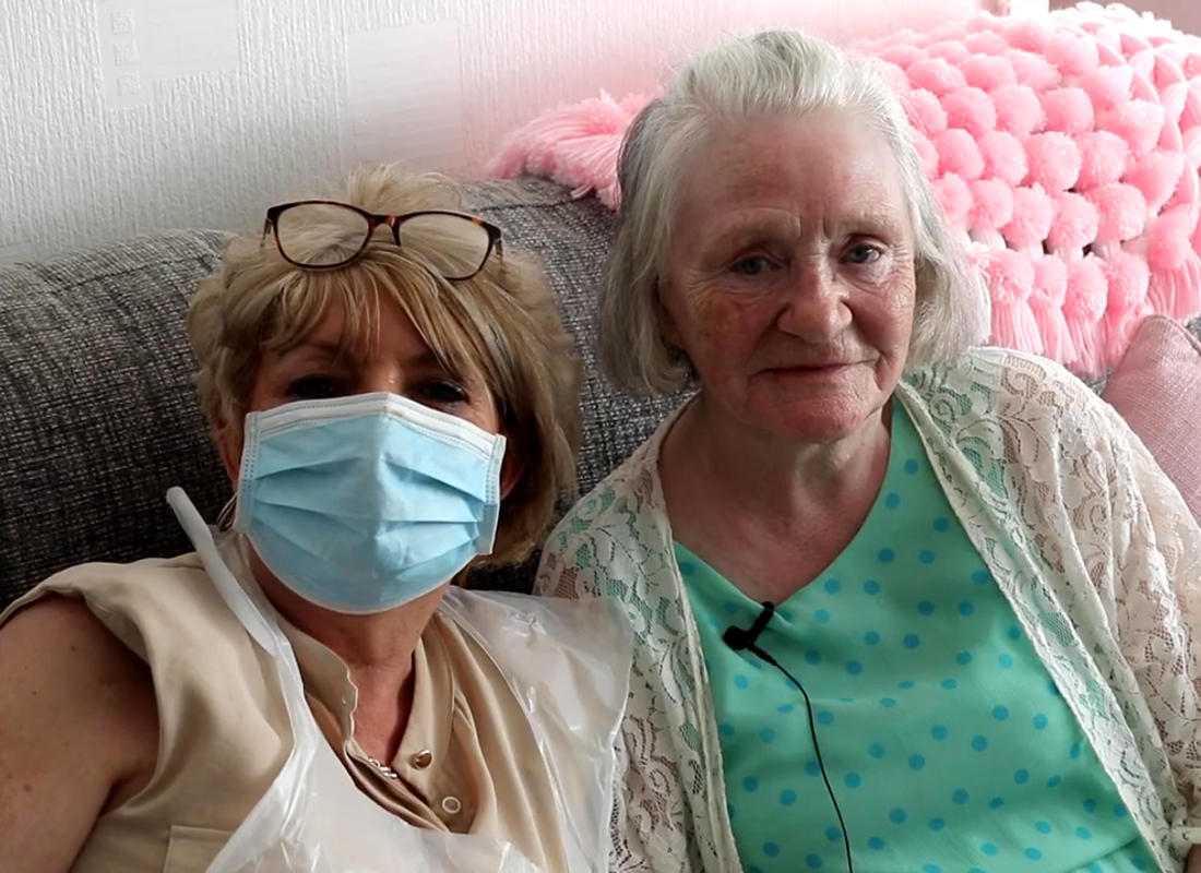 two residents sat on their sofa, one wearing COVID PPE